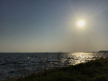 Scenic view of sea against bright sun