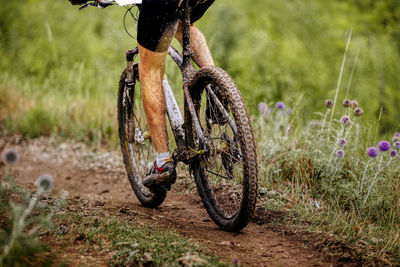 Low section of man with bicycle on dirt road