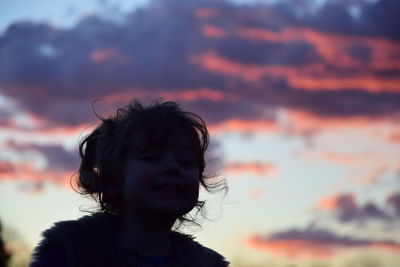 Silhouette girl against cloudy sky at sunset