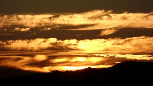 Silhouette landscape against dramatic sky during sunset