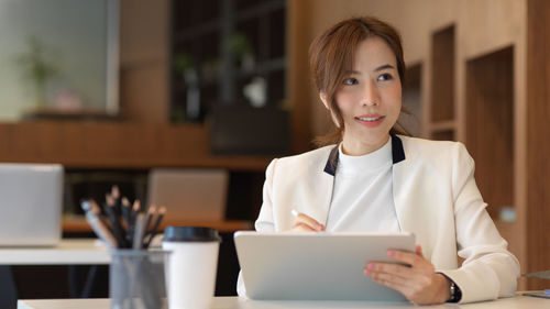 Mid adult woman using mobile phone at table