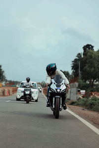 Front view of man riding motor scooter on road