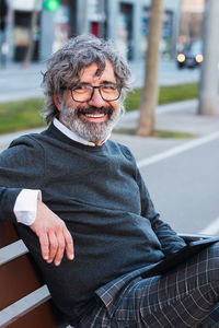 Portrait of smiling senior man sitting on bench