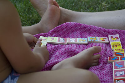 Low section of baby with mother playing while sitting on field