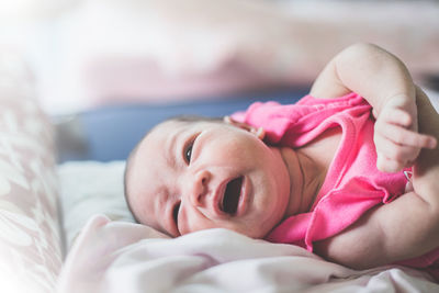 Close-up of baby girl lying on bed