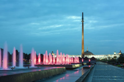 Illuminated buildings in city against sky at dusk