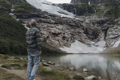 Rear view of man standing on rock by lake