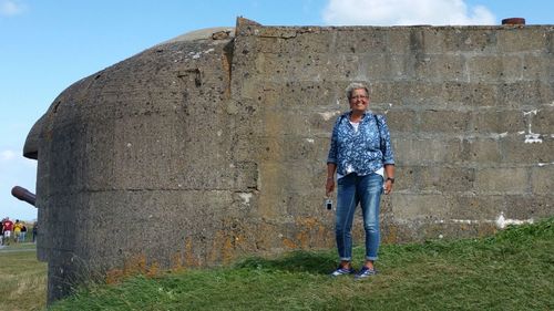 Full length of woman standing against wall at longues-sur-mer battery