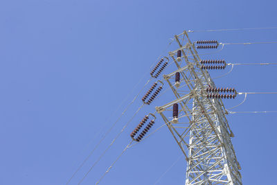 Low angle view of electricity pylon against clear sky