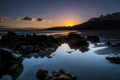 Rocks on sea against sky during sunset