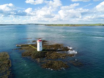 Lighthouse by sea against sky