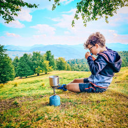 Boy on grassy field against sky