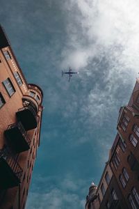 Low angle view of airplane flying in building against sky