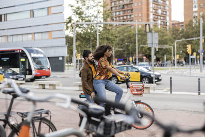 Young man sitting with girlfriend on bicycle at footpath