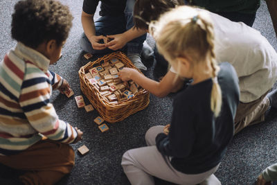 High angle view of preschool kids playing puzzle game while sitting in classroom at day care center