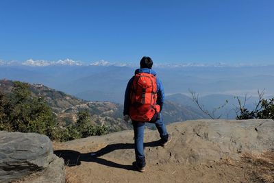 Rear view of man looking at mountains against sky