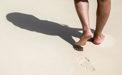 Low section of woman walking on sand at beach