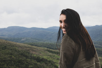 Portrait of smiling woman on mountain against sky
