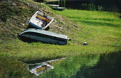 Boat moored on field by lake