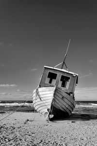 Fishing boat on beach against sky