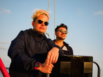 Two persons on a sailboat, one person steering wheel sailing yacht