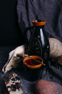 Old dog skull, jug and stones on witch table. enchanted drink with flower petals