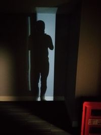 Silhouette person standing against wall at home