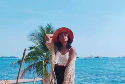 Young woman smiling at beach against sky