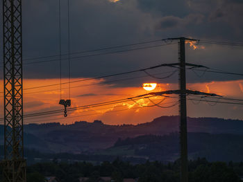 Silhouette electricity pylon against sky during sunset