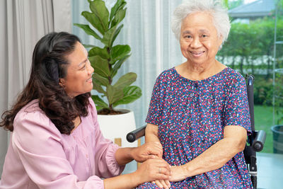 Portrait of smiling friends using mobile phone at home