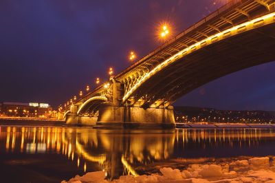 Illuminated bridge over river at night