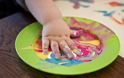 Cropped image of hand on colorful watercolor paints in plate