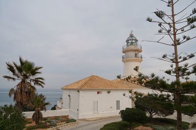 View of lighthouse by building against sky