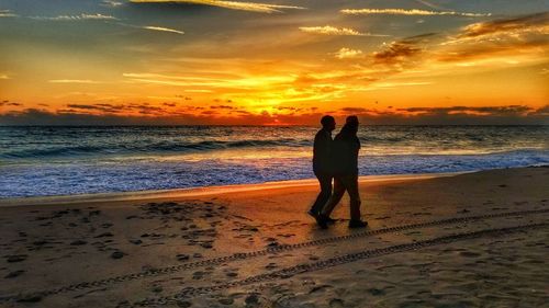 Woman standing on beach against sky during sunset