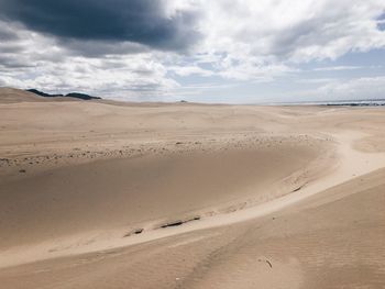 Scenic view of desert against cloudy sky