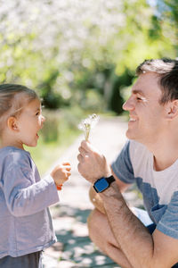 Side view of boy blowing bubbles while sitting outdoors