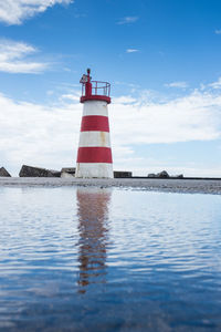 Lighthouse by sea against sky