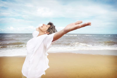 Side view of senior woman standing at beach