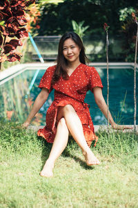 Portrait of woman sitting on land against swimming pool