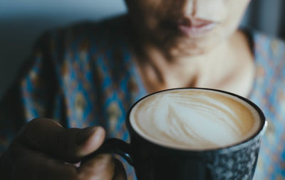 Midsection of woman holding coffee cup in cafe