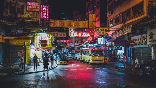 People on street by buildings at night