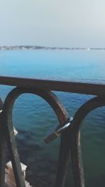 Close-up of rusty metal railing by sea against sky