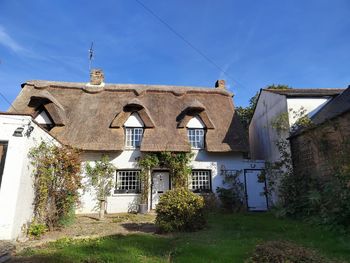 Low angle view of cute thatched cottage in grantchester against clear blue sky