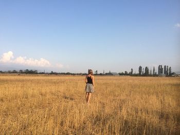 Woman standing on field against sky