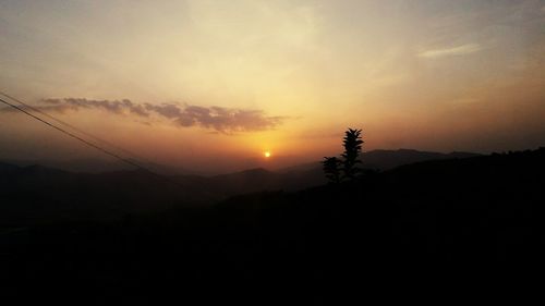 Scenic view of silhouette mountains against orange sky