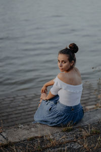 Portrait of young woman sitting on shore