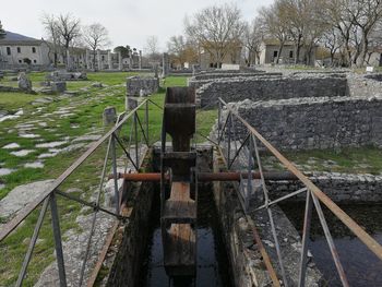 Metallic structure in cemetery against sky