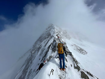 Man skiing on snowcapped mountain against sky