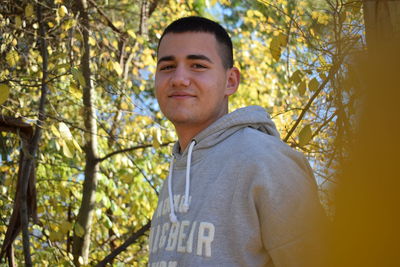 Portrait of young man standing against trees in forest