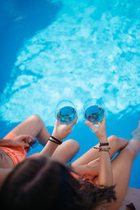 Drinking wine by the pool.two glasses of blue wine. couple by the pool